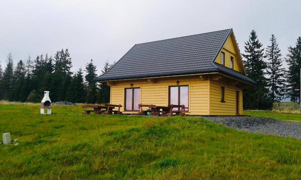 a small yellow house with a picnic table in a field at Domki na Tynioku in Koniaków