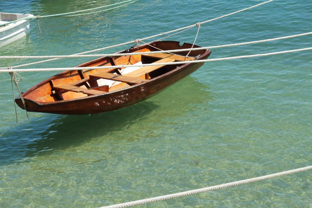 a wooden boat tied to a rope in the water at Sur le chemin de la plage in Cherbourg en Cotentin