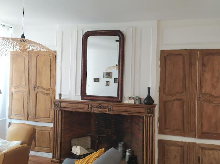 - un salon avec un miroir au-dessus d'une cheminée dans l'établissement À l'ombre de l'abbatiale, 90 m² rénovés 3 chambres, à Aurillac