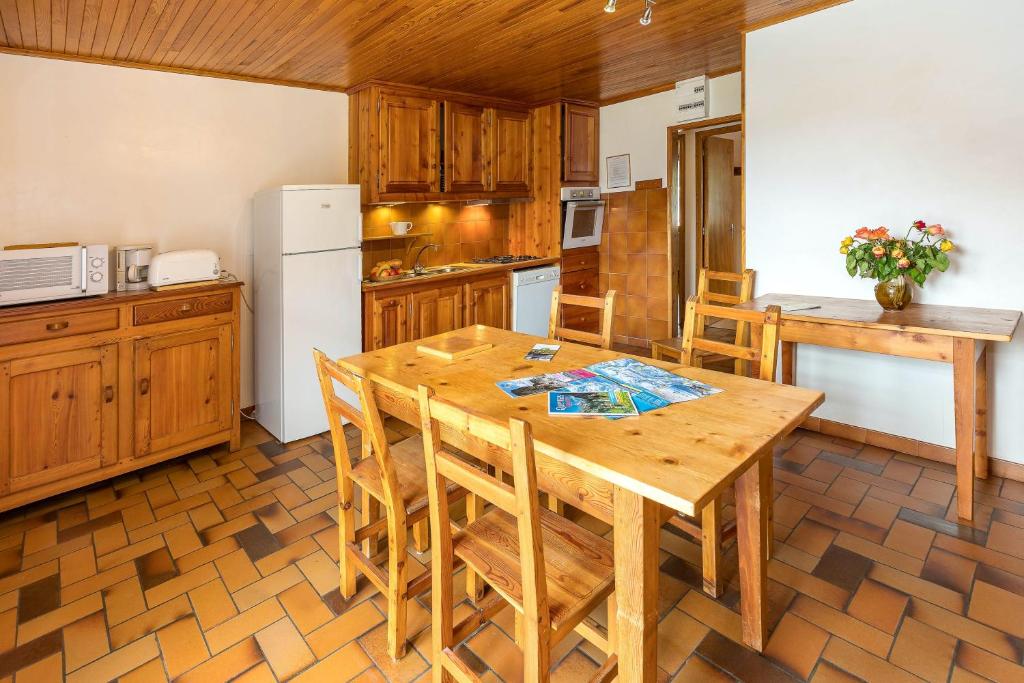 uma cozinha com uma mesa de madeira com cadeiras e um frigorífico em Appartement de 2 chambres avec balcon et wifi a Le Coin em Arvieux