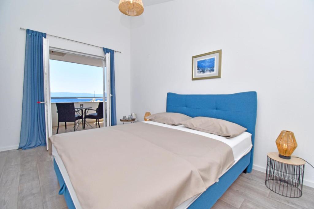 een slaapkamer met een blauw bed, een raam en een tafel bij Maya's Room in Tučepi