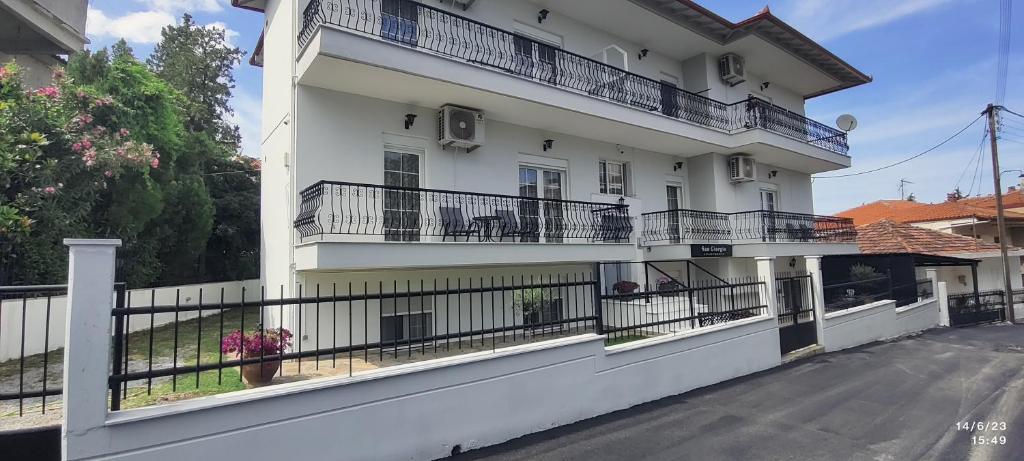 a white building with balconies on a street at San Giorgio in Litochoro