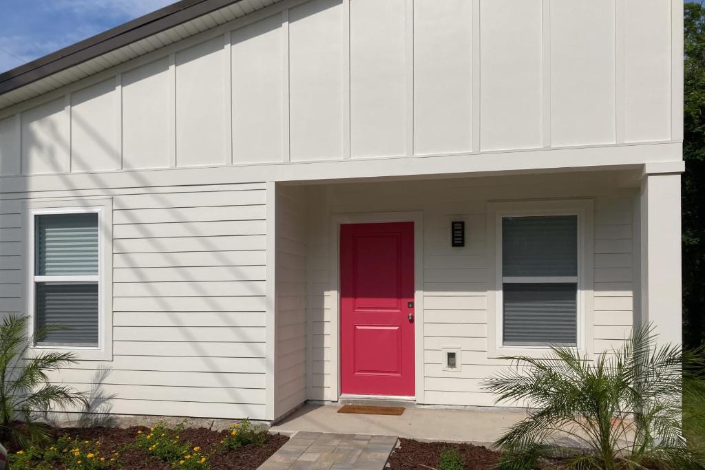 uma porta vermelha do lado de um edifício branco em The Blue Heron Cottage em Saint Augustine