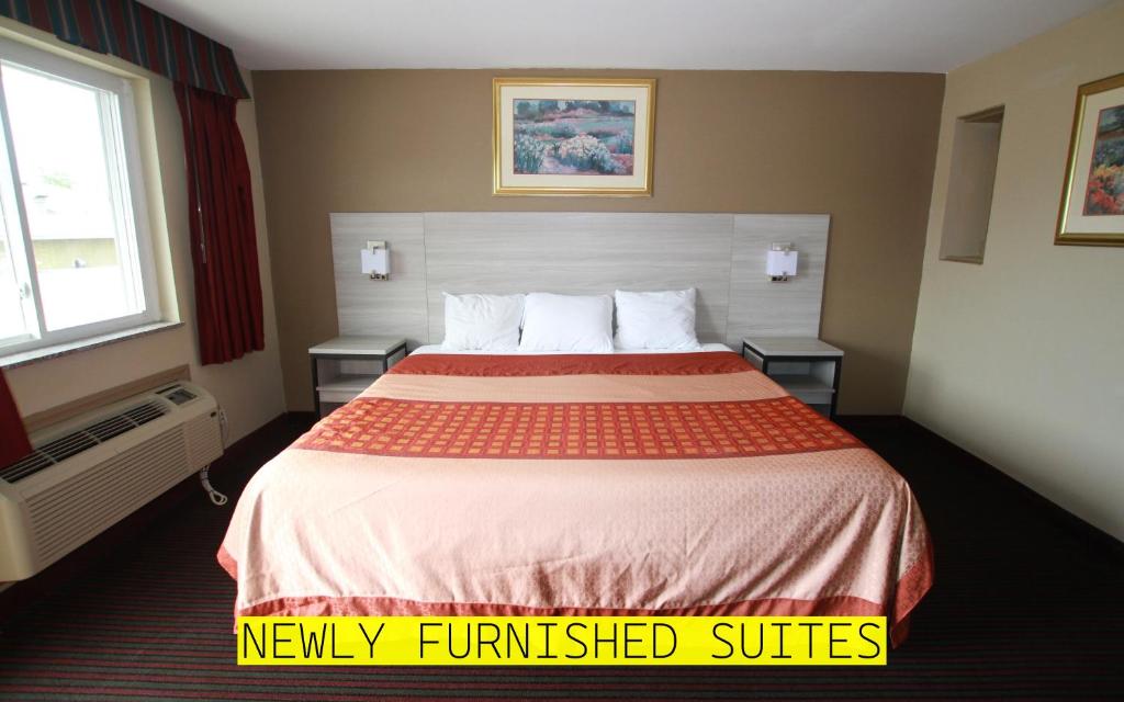 a hotel room with a large bed with two tables at Travel Inn & Suites Flemington in Flemington