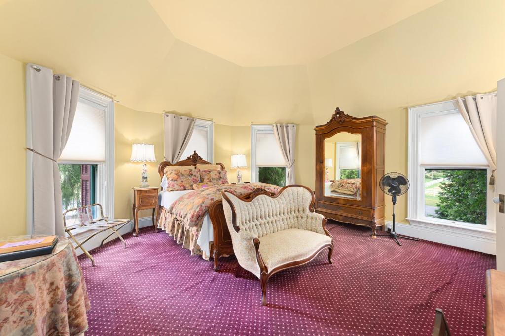a bedroom with a bed and a chair and windows at The Gables Wine Country Inn in Santa Rosa