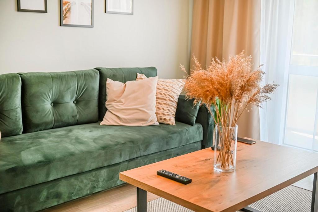 un sofá verde en una sala de estar con mesa en Apartment 93B, en Nowa Sól