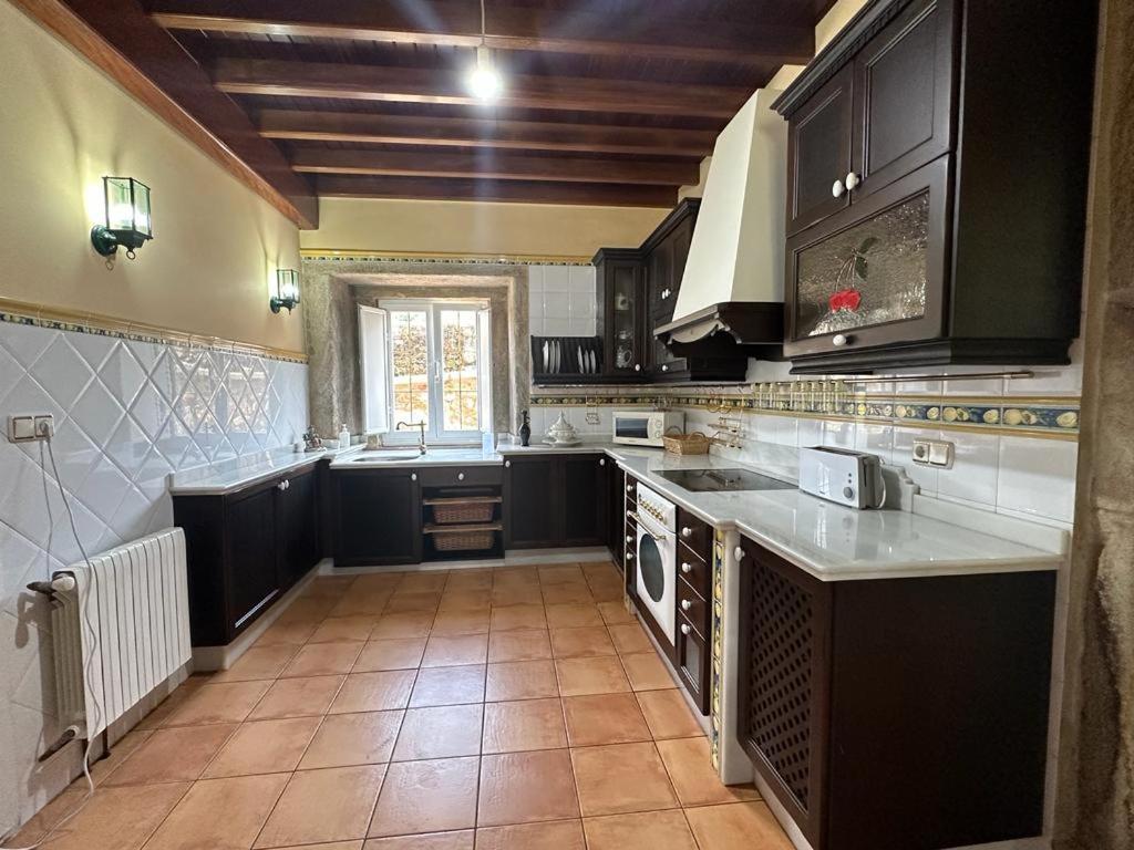 a kitchen with black cabinets and a tile floor at Casa de Romaxe in Muros