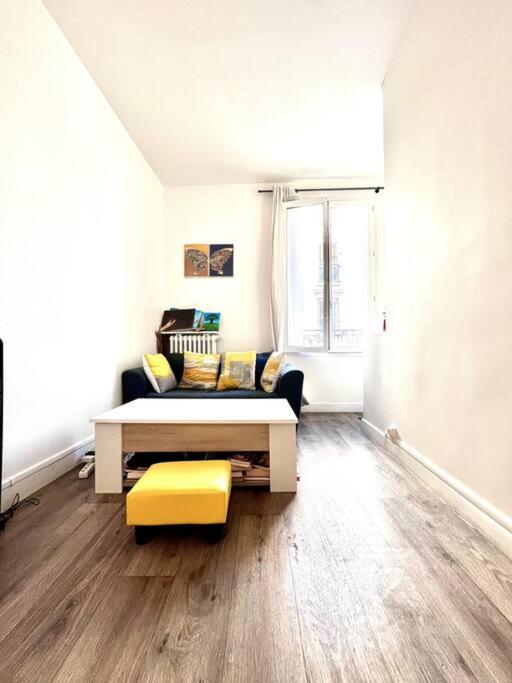 - un salon avec un lit et un tabouret jaune dans l'établissement Appartement de charme tout équipé à Paris, pour 4 personnes, 2 grands lits, à Levallois-Perret