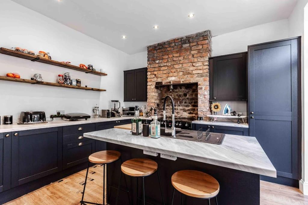 eine Küche mit blauen Schränken und einer Theke mit Stühlen in der Unterkunft Orange Rentals-Characteristic Victorian terrace 5 bedroom house in Liverpool