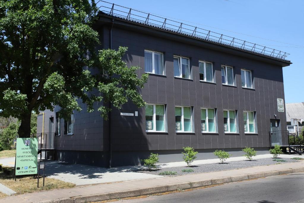un edificio negro al lado de una calle en Akmenės svečių apartamentai Šypsena, en Akmenė