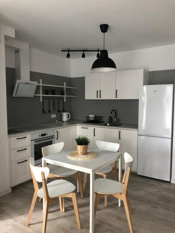 uma cozinha com uma mesa e cadeiras e um frigorífico branco em Apartament Skandynawski em Chojnice