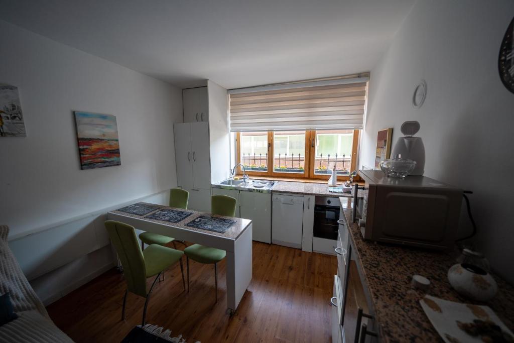 een keuken met een kleine tafel en groene stoelen bij Apartman Daris in Sarajevo