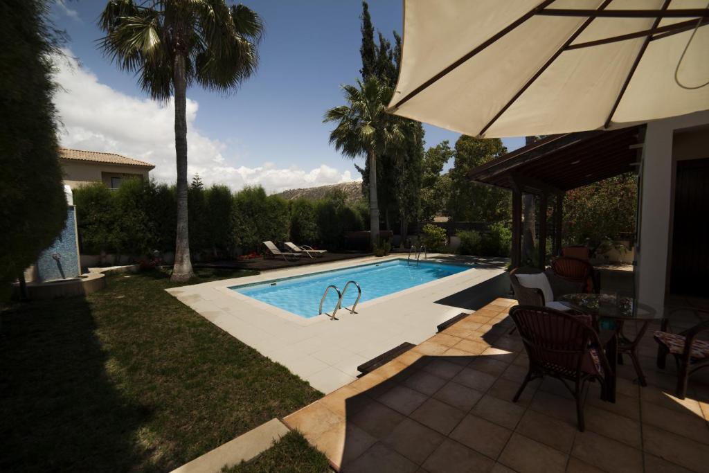 a swimming pool with a table and an umbrella at El Marco Villa in Pissouri