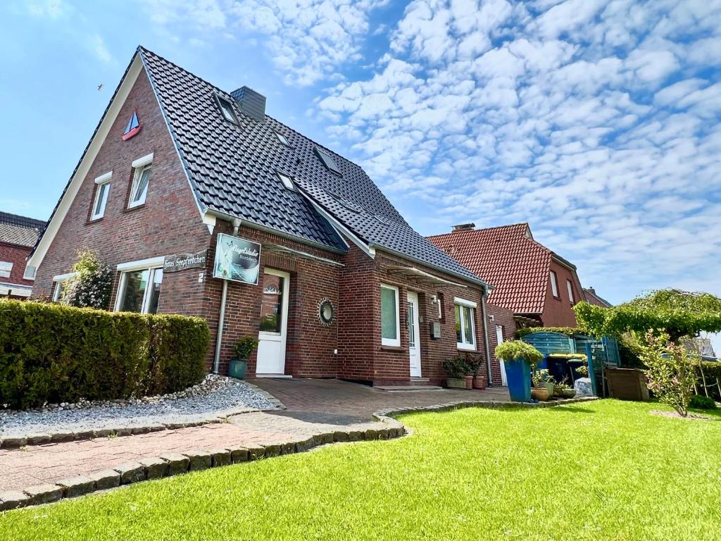 a red brick house with a grass yard at Pension Seepferdchen in Norddeich