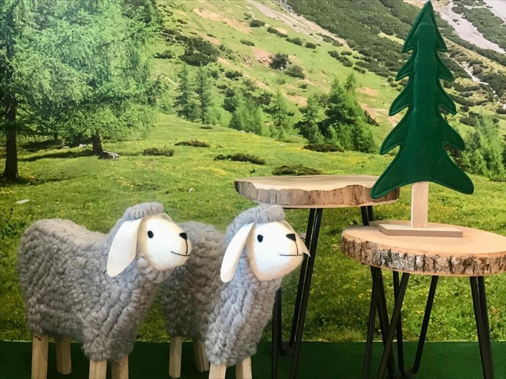 two sheep standing next to two tables with a christmas tree at Wellnessapartment Alpenland Top 22 in Seefeld in Tirol