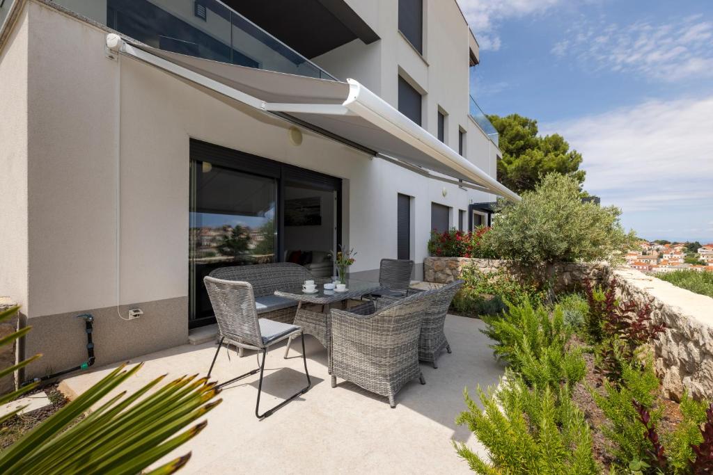 een patio met een tafel en stoelen buiten een gebouw bij Apartments Tony in Mali Lošinj