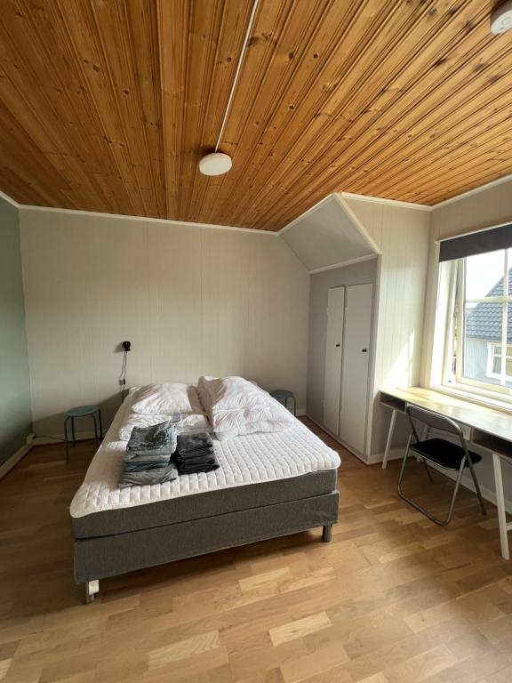 a bedroom with a bed with a wooden ceiling and a desk at Koselig hus i havna in Svolvær