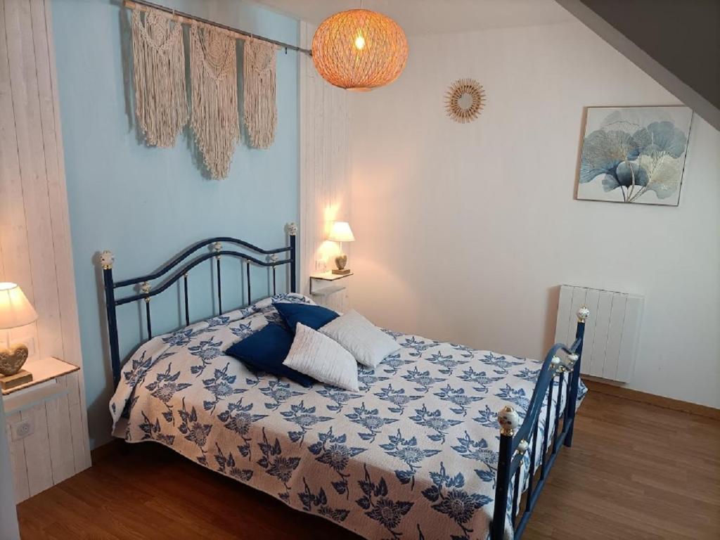 a bedroom with a bed with a blue and white comforter at Le Moulin de Benneville chambres d'hôtes, petit déjeuner compris in Cahagnes