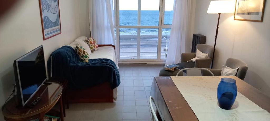 uma sala de estar com um sofá, uma televisão e uma mesa em Ventana al Mar em Puerto Madryn