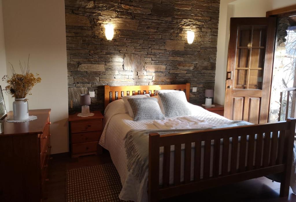 um quarto com uma cama e uma parede de tijolos em Casa do Parâmio - Montesinho em Parâmio