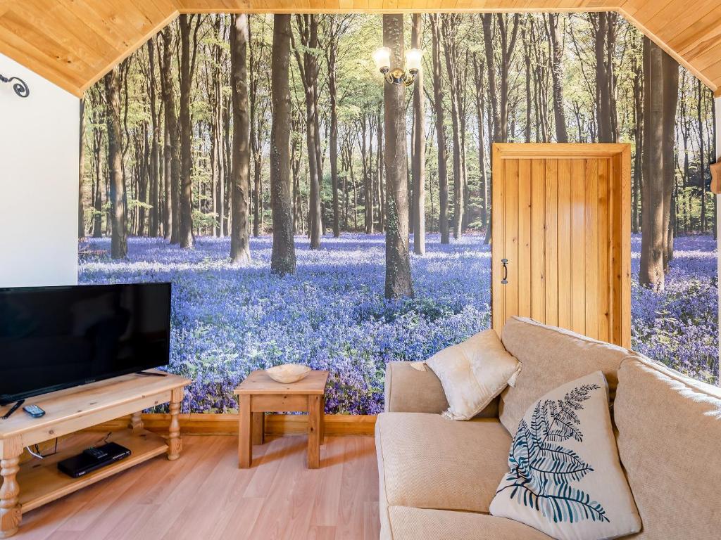 Bluebell Cottage - Uk36669 في Goulsby: غرفة معيشة مع لوحة جدارية لغابة بها زهور زرقاء