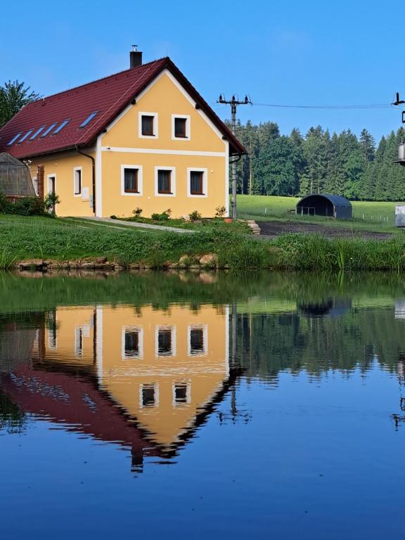 Horní Stropnice的住宿－RYBÁŘSKÁ CHALUPA，水中倒映的黄色房子