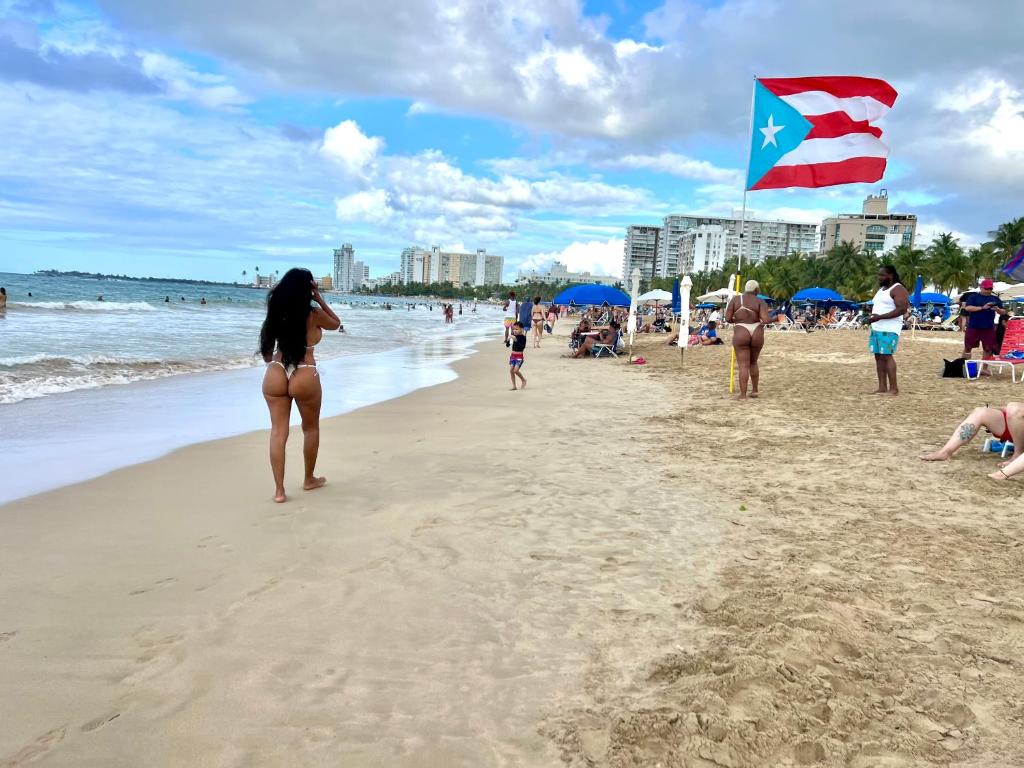 a woman standing on a beach with a flag at Ocean View apt on Isla Verde in a 14th floor in San Juan