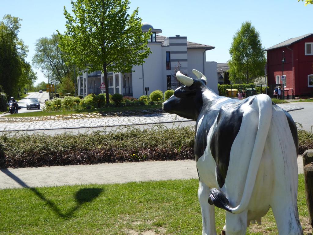 een standbeeld van een koe in het gras bij Sandsturm in Warnemünde