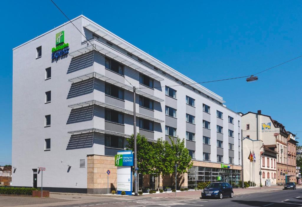 a large white building on a street with a car in front at Holiday Inn Express Frankfurt Messe, an IHG Hotel in Frankfurt