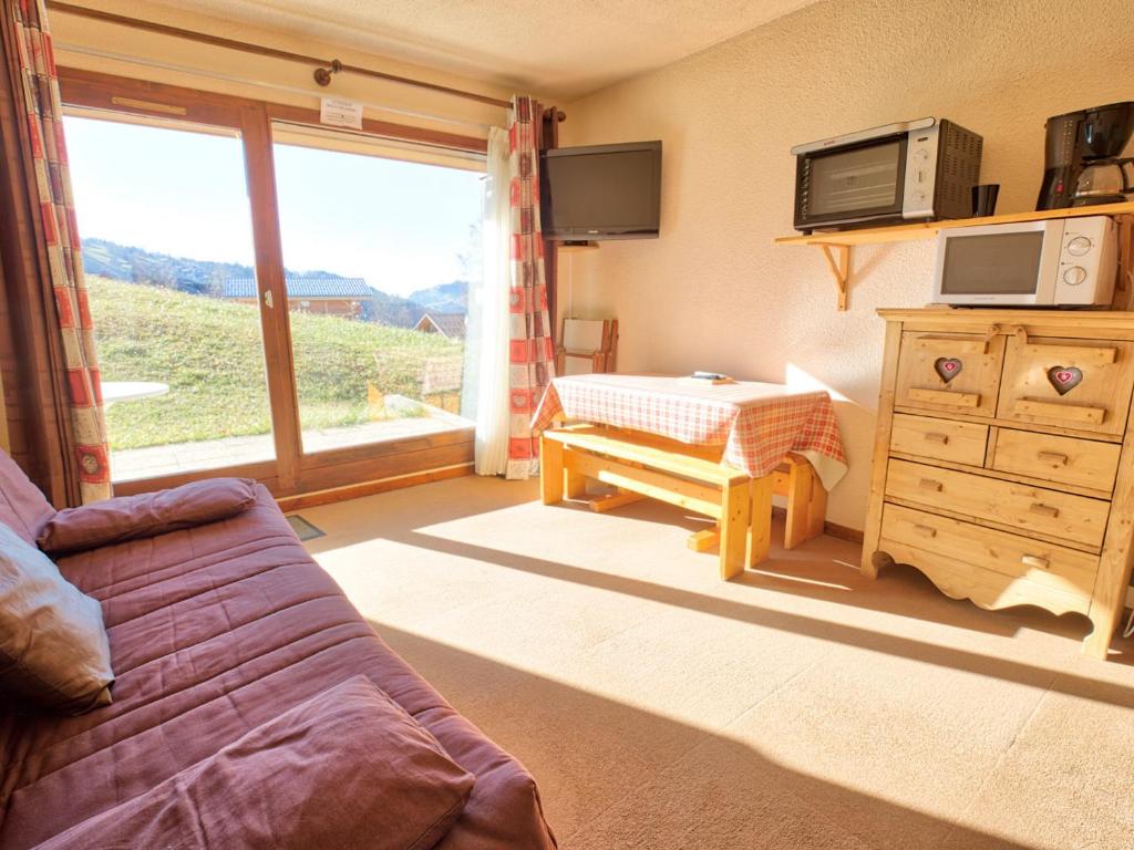 a living room with a couch and a large window at Studio calme avec terrasse jardin et parking - 4 pers. - FR-1-505-11 in Notre-Dame-de-Bellecombe