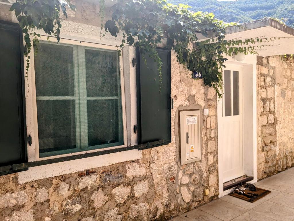 a stone house with a window and a door at Nadalina Guest House in Kotor