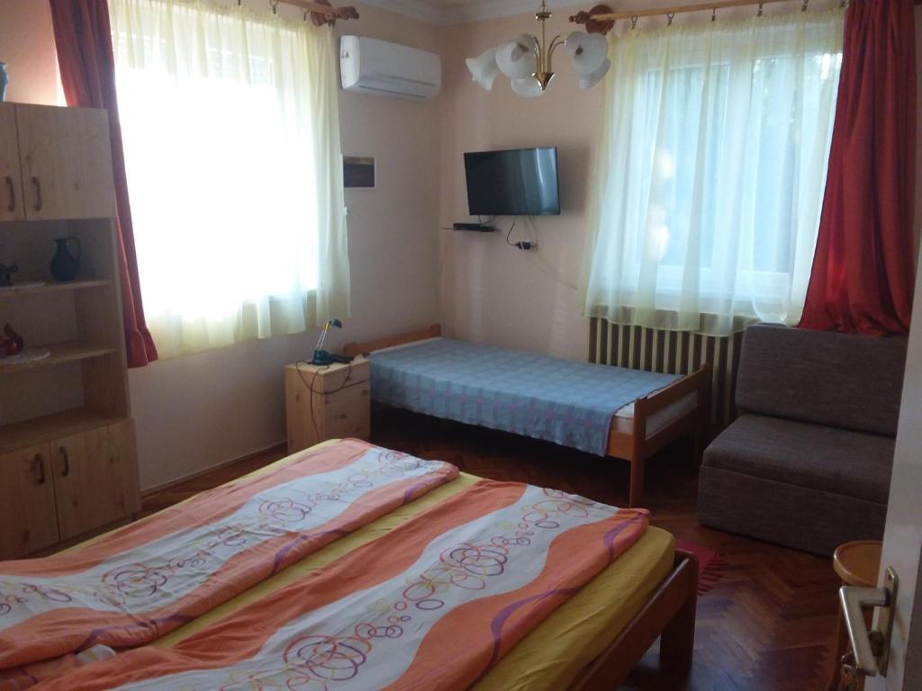 a small bedroom with two beds and a chair at Gál Apartman 2 in Hajdúszoboszló
