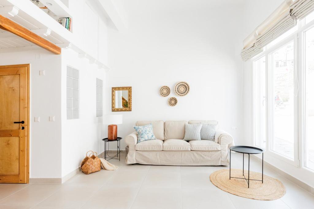 a white living room with a couch and a window at Helona guesthouse, Skopelos in Skopelos Town