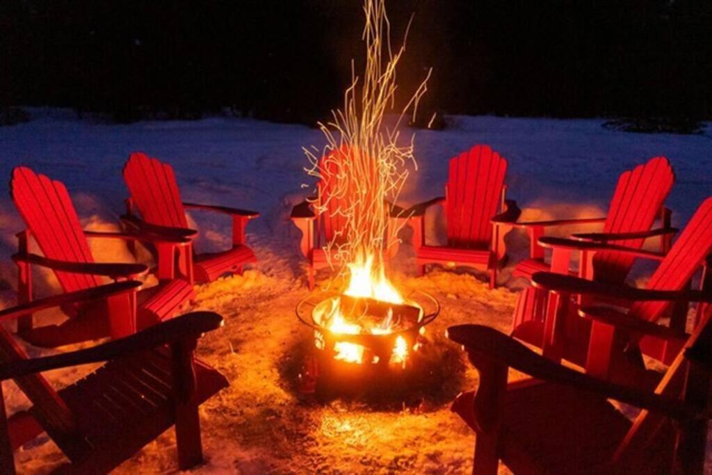 een vuurplaats in het zand met stoelen eromheen bij Private 5 BR Muskoka Cottage Firepit+BBQ+Wi-Fi in Bracebridge