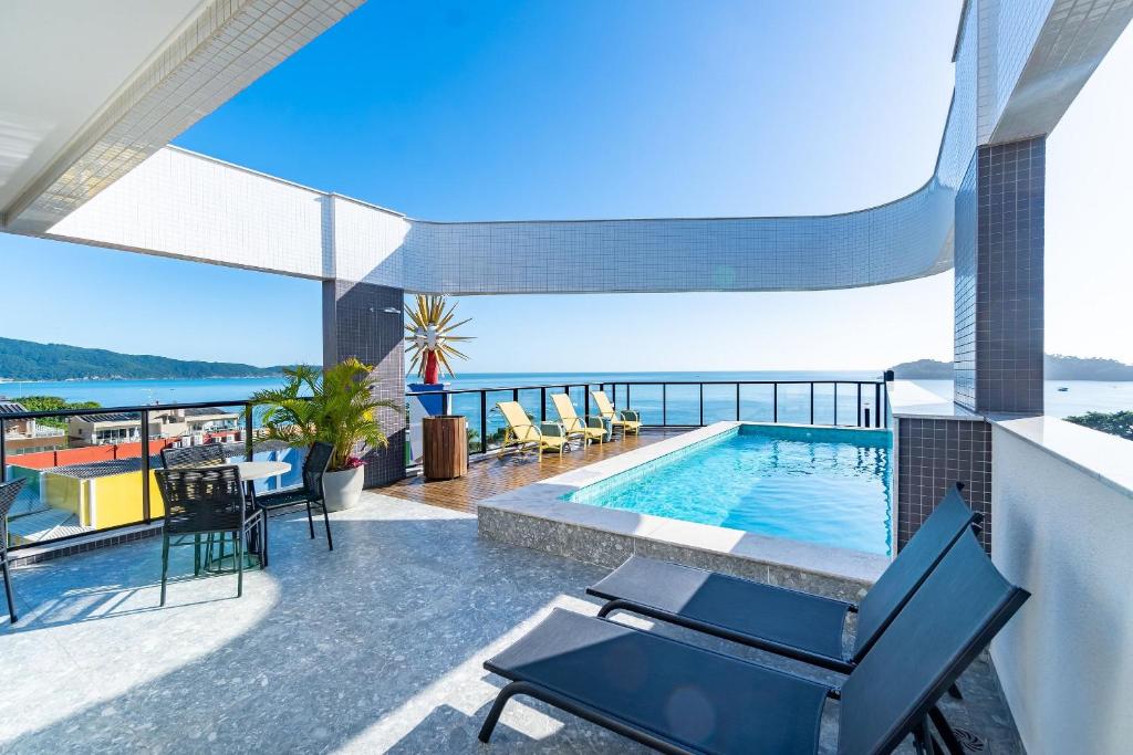 a house with a swimming pool and a view of the ocean at Aion Suítes - Luxuoso Loft, Praia de Bombinhas in Bombinhas