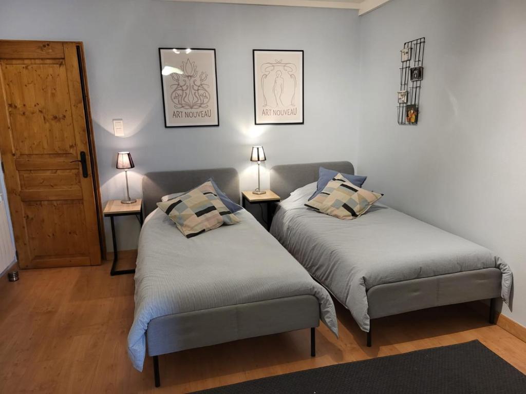 2 Betten in einem Zimmer mit 2 Lampen und einer Tür in der Unterkunft Le Studio in Blénod-lès-Pont-à-Mousson
