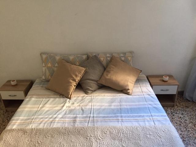 1 cama con 3 almohadas y 2 mesas en Appartamentino in Piazza en Trevignano Romano