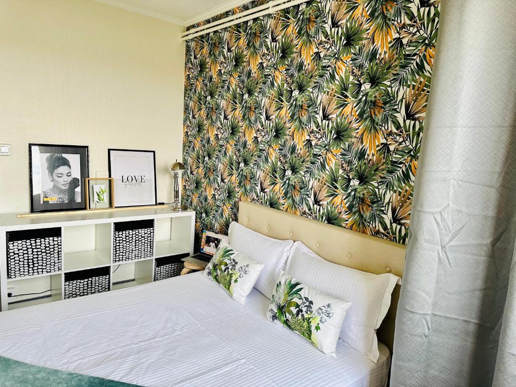 a bedroom with a bed with a tropical wallpaper at Grand appartement Bron centre proche Eurexpo et Groupama in Bron