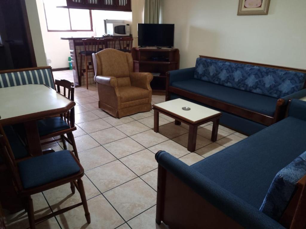 sala de estar con sofás azules, mesa y sillas en Hotel Residencial Itapema, en Itapema