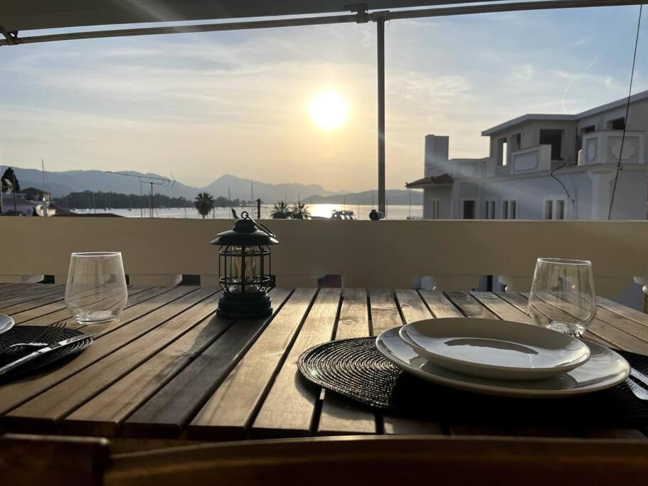 una mesa de madera con un plato y copas de vino. en Sunset Haven en Poros