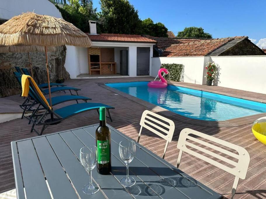 una botella de vino en una mesa junto a la piscina en Casa da Portelinha, en Castelo de Paiva