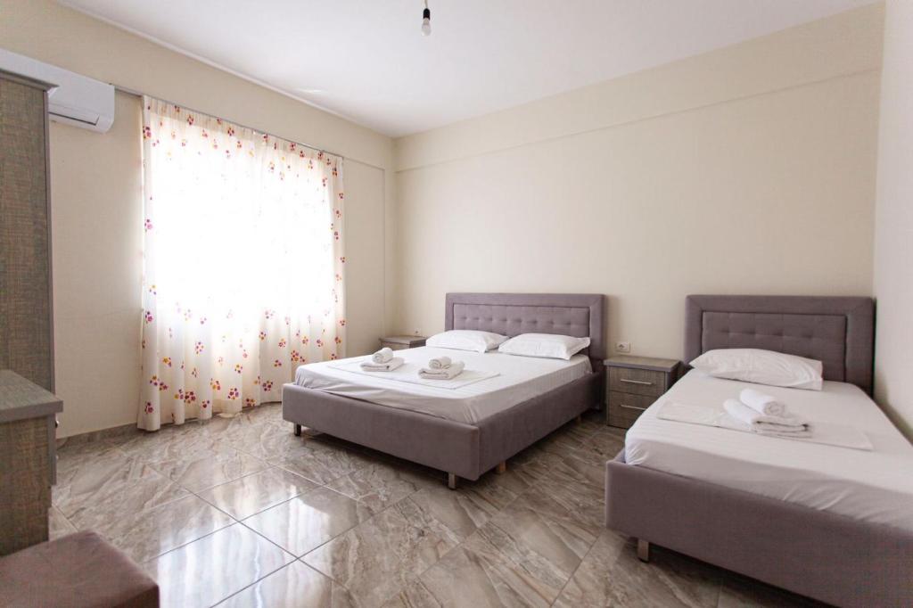 a bedroom with two beds and a window with a window treatment at Vila Zisi Himare in Himare