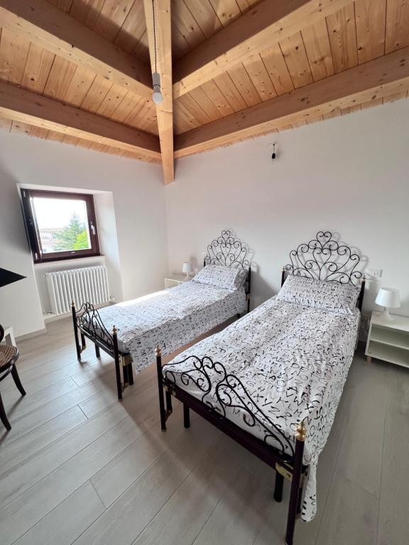 two beds in a bedroom with a wooden ceiling at La Piazzetta in LʼAquila