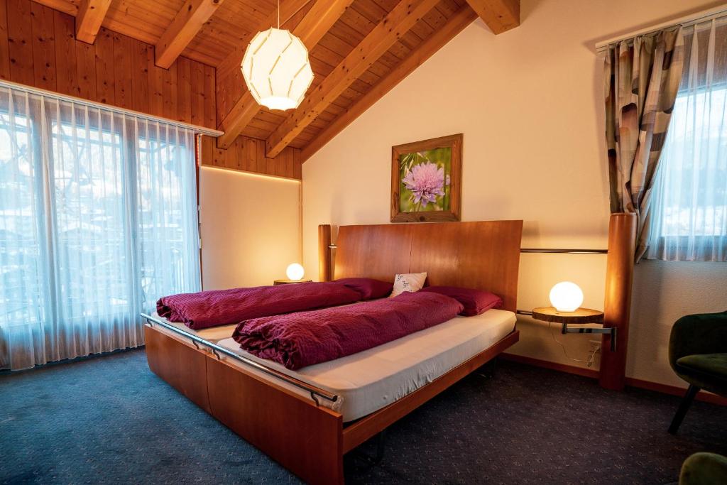 ein Schlafzimmer mit einem großen Bett mit roter Bettwäsche in der Unterkunft Kulinarik & Geniesser Hôtel STRAUSS in Fiesch