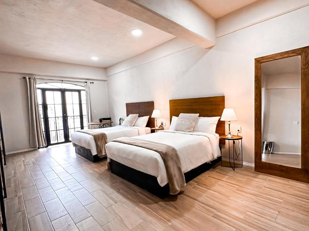 a hotel room with two beds and a mirror at Hotel Santa María in Taxco de Alarcón