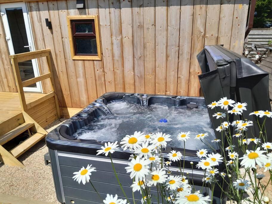 a hot tub in a garden with daisies at The Lodge 