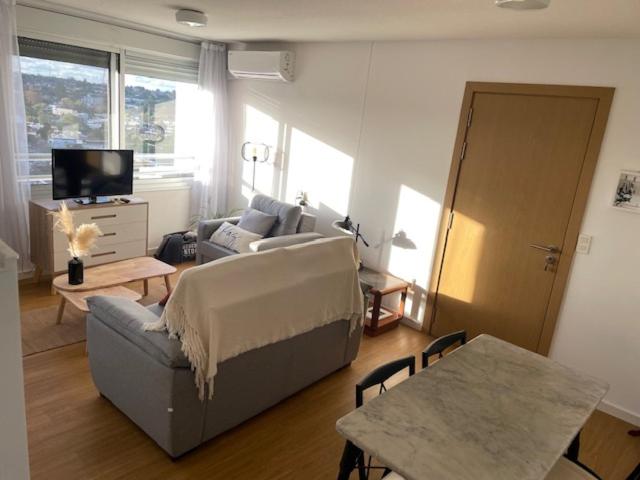 ein Wohnzimmer mit einem Sofa und einem Tisch in der Unterkunft Encantador apartamento en Malvín in Montevideo
