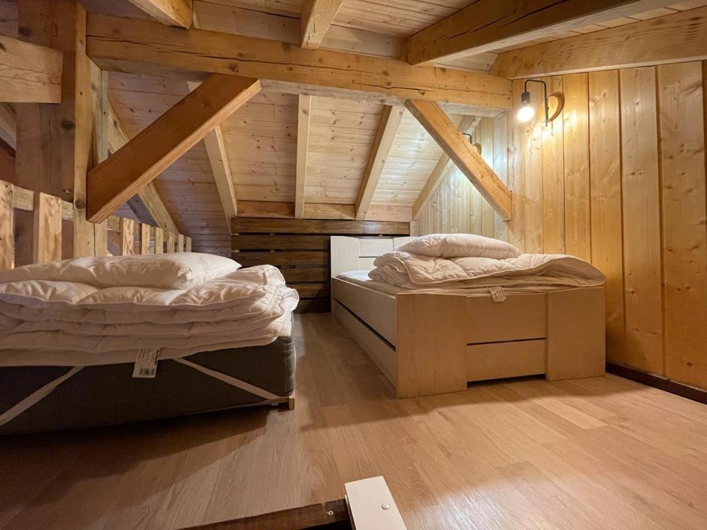 two beds in a room with wooden walls at La cabane de dany in La Bresse
