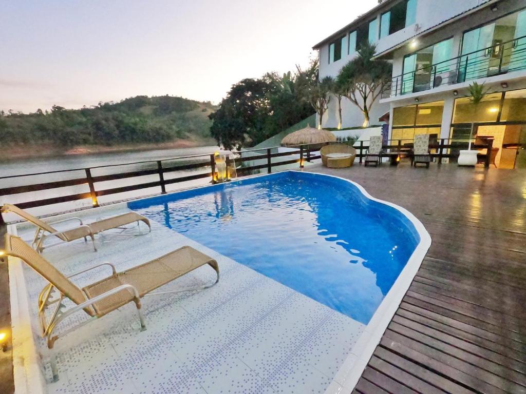 een zwembad met 2 stoelen en een gebouw bij Mansão pé na água - represa de Igaratá para 15 pessoas in Igaratá