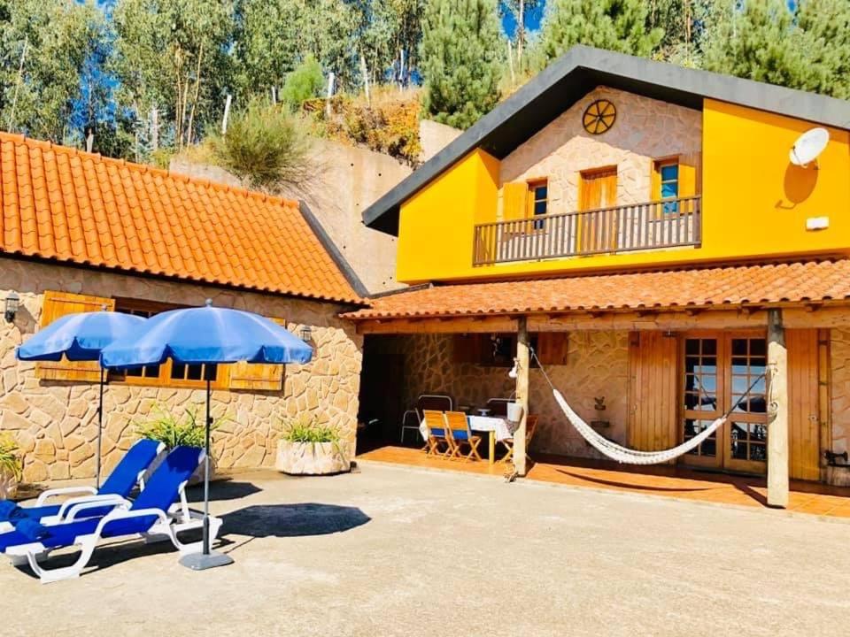 a house with chairs and an umbrella and a hammock at Villa Safari Charm in Ribeira Brava